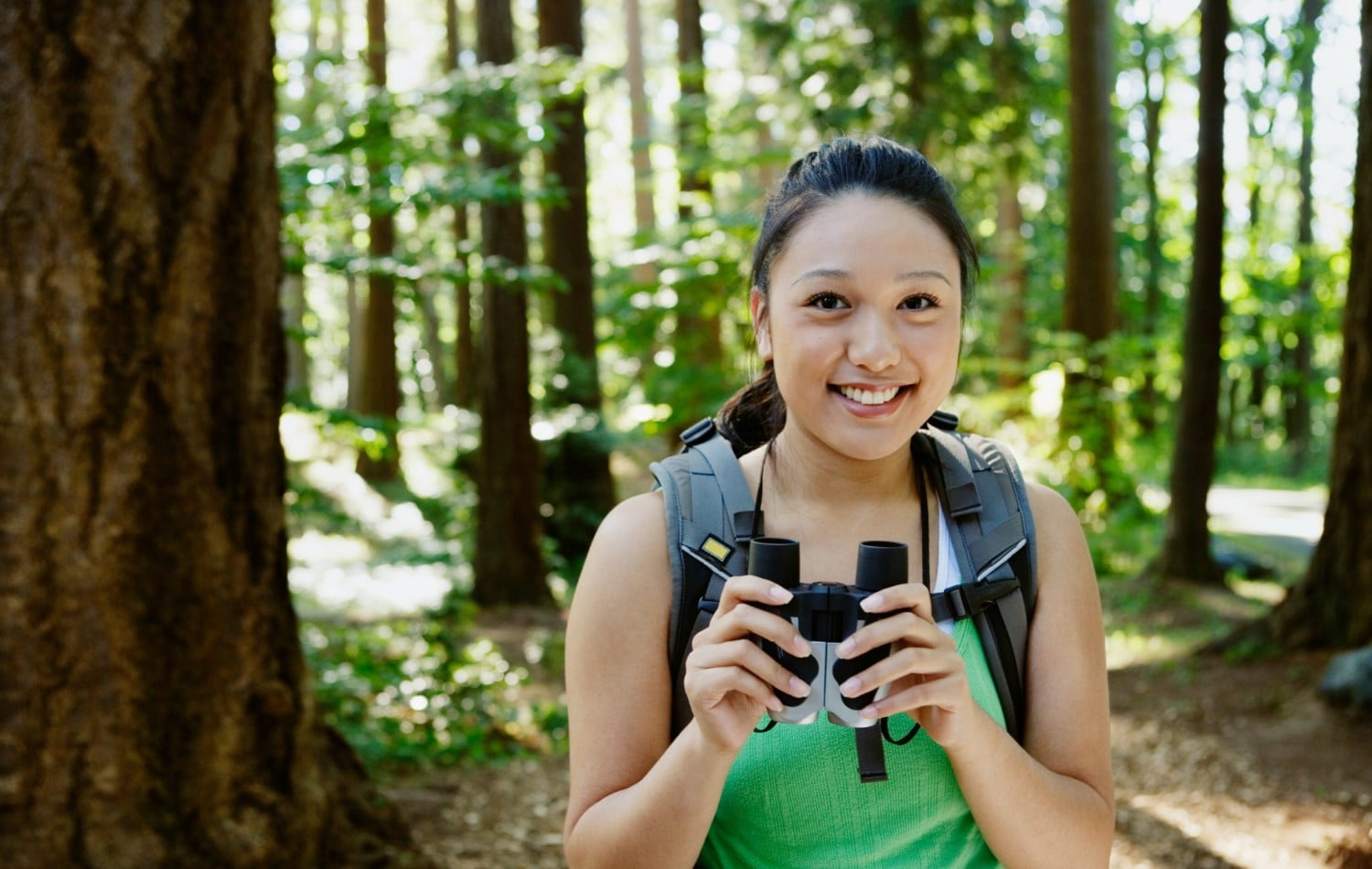 woman holding a pair of binoculars in the woods