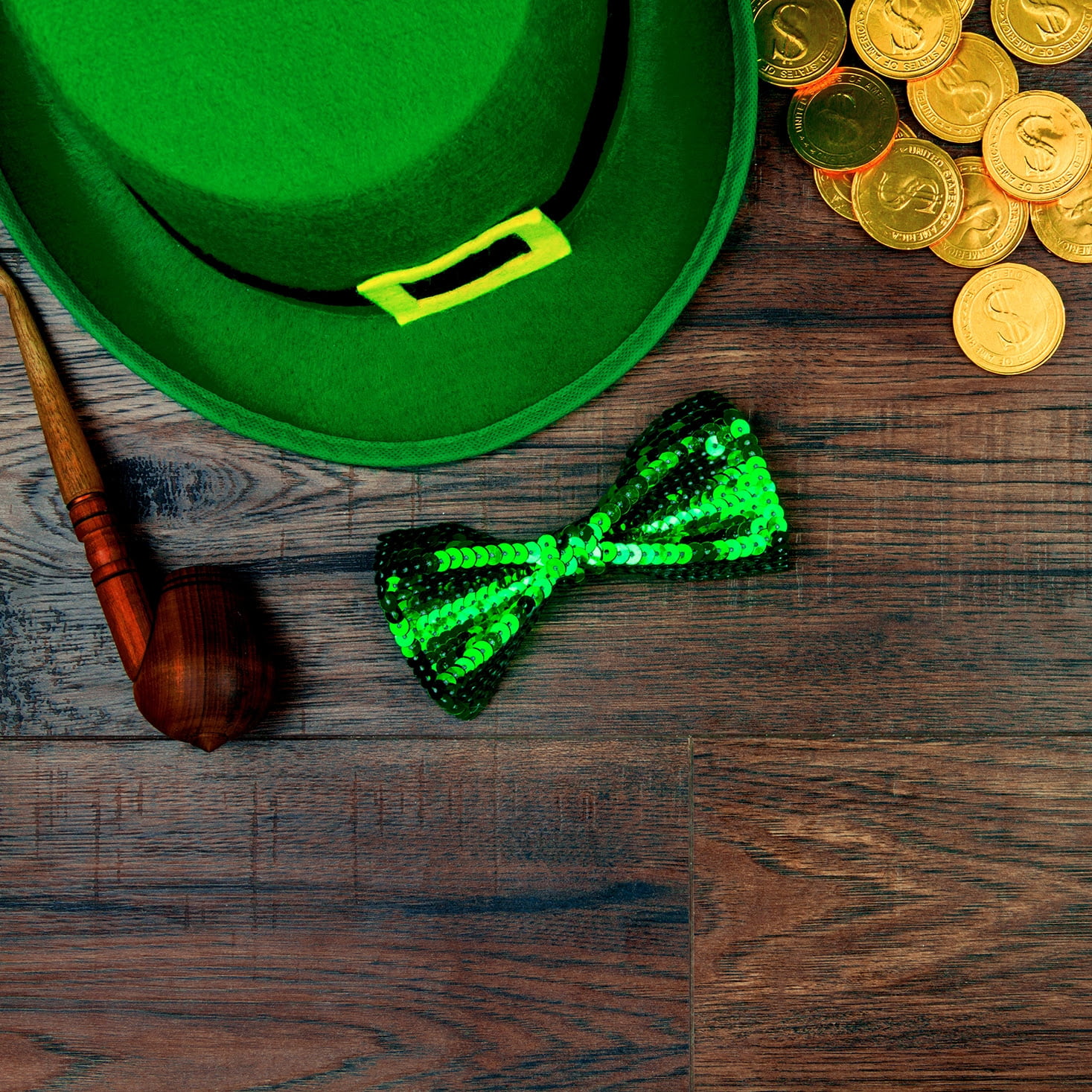 Saint Patrick's Day. Green hat of leprechaun, green bow tie, smoking pipe and gold coins on wooden background