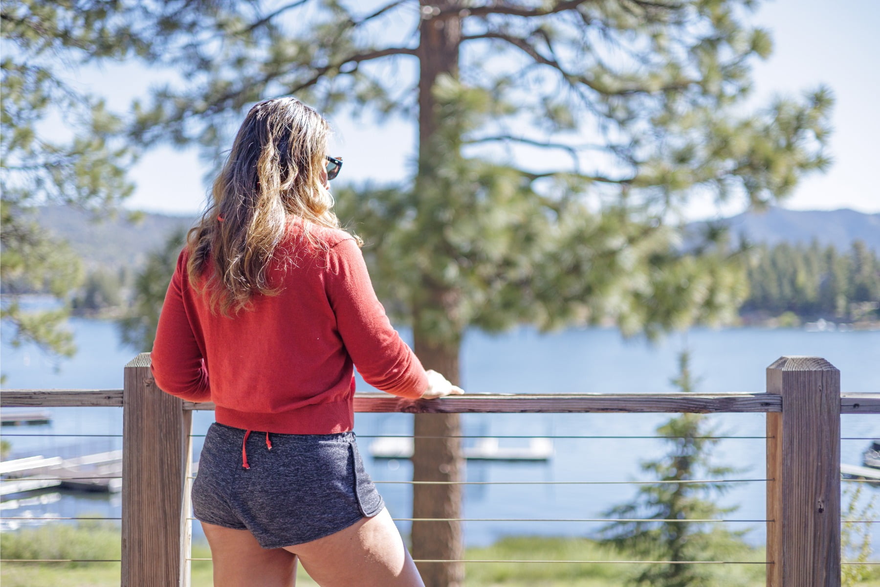 Guest enjoys views of beautiful Big Bear Lake and southern California's mountains, boats, boat docks and fishing at Lakefront Raccoon's Nest deck